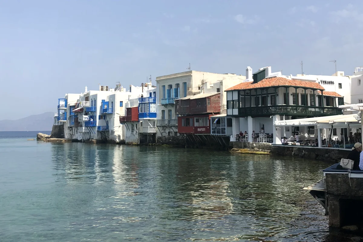 Whitewashed seaside houses with colourful balconies along clear blue water